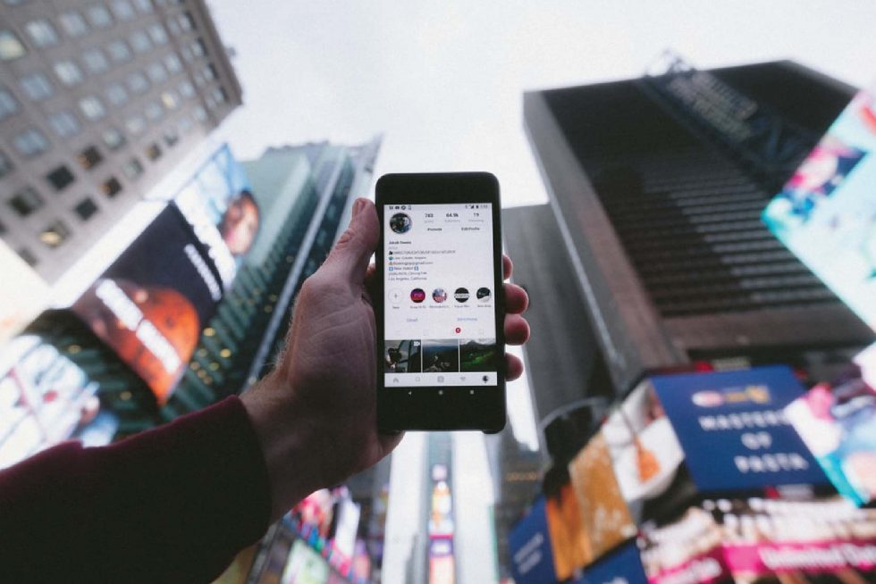 hand holding phone with building in the background